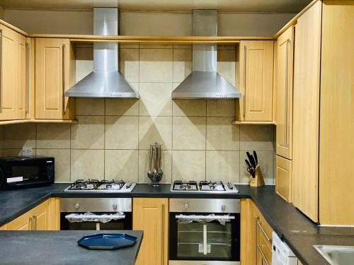 uma cozinha com armários de madeira e electrodomésticos de aço inoxidável em Callerton House em Newcastle upon Tyne