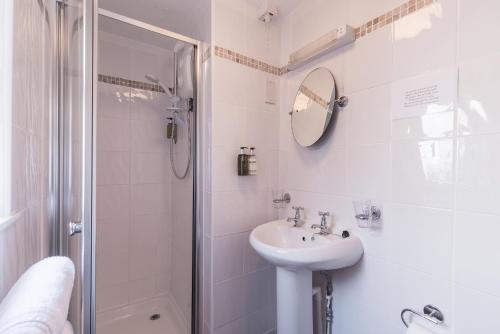 a white bathroom with a sink and a shower at The Mount Pleasant Hotel in Sidmouth