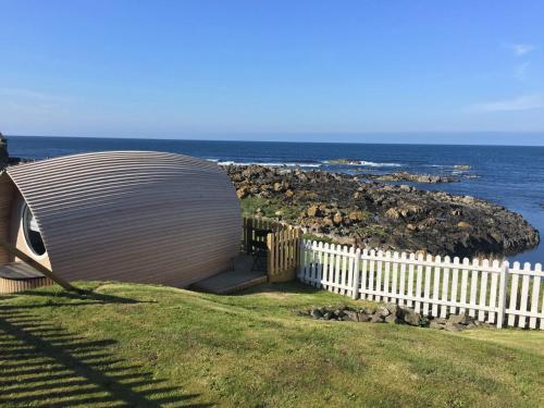 a building sitting on top of a field next to the ocean at Door to the Shore - Seafront Cottages in Sandhaven