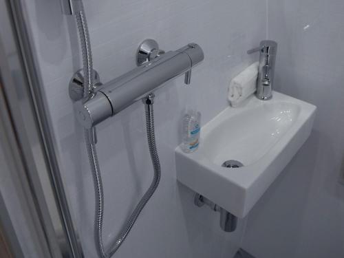 a shower nozzle next to a sink in a bathroom at Door to the Shore - Seafront Cottages in Sandhaven