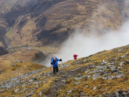 two people hiking up a mountain in the clouds at Door to the Shore - Seafront Cottages in Sandhaven