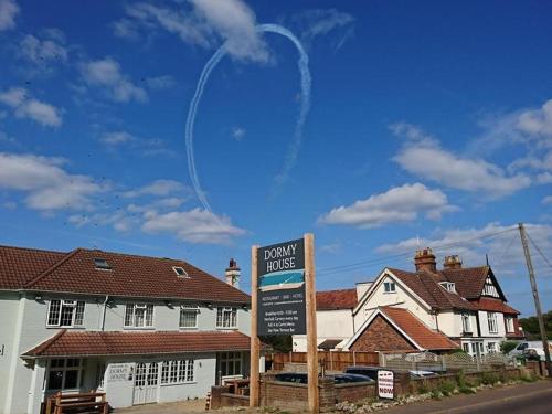 a sign in front of a house with a contrail in the sky at The Dormy House Hotel in Cromer