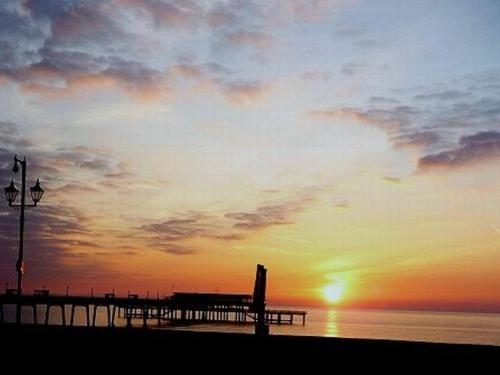 a beach with a pier and the sunset in the background at Dunkerley's Hotel and Restaurant in Deal