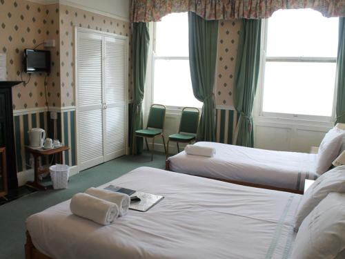 a hotel room with two beds with towels on them at A MAIDEN REST in Weymouth