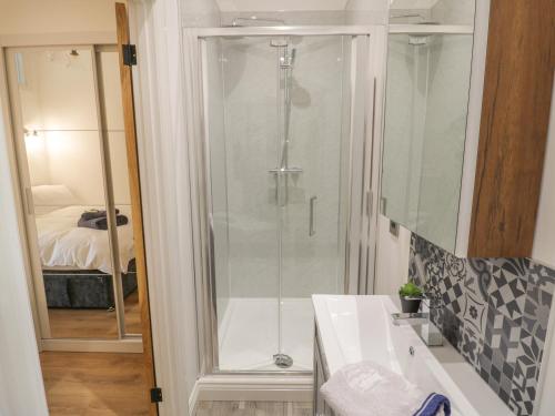a bathroom with a shower and a white sink at The Barn in Redditch