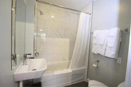 a bathroom with a sink and a tub and a shower at Harrison Spa Motel in Harrison Hot Springs