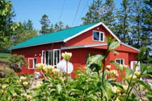 ein rotes Haus mit grünem Dach in der Unterkunft Farm&Inn Imodango Mura in Abashiri
