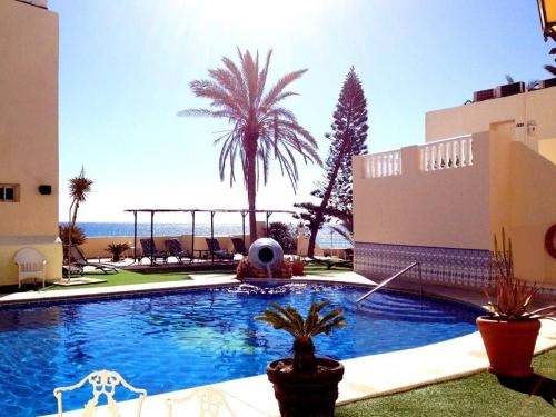 une piscine bordée de palmiers et un bâtiment dans l'établissement Hotel El Dorado, à Carboneras