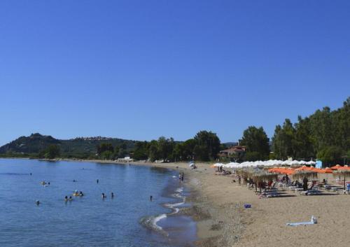 a beach with a bunch of people in the water at Thea, Agios Andreas in Néa Koróni