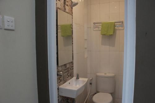 a bathroom with a sink and a toilet and a mirror at The Peak Guest House in Jember