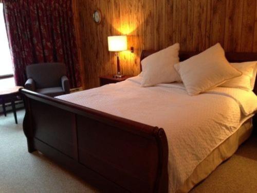 ein Schlafzimmer mit einem großen Bett und einem Stuhl in der Unterkunft Evergreen Valley Inn in North Lovell