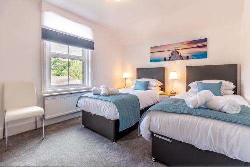 Guest Homes - Farningham Residence في كاترهام: غرفة نوم بسريرين ونافذة