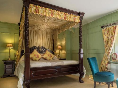 a bedroom with a canopy bed and a blue chair at The Fauconberg in Coxwold