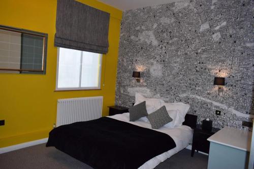 1 dormitorio con cama y pared de ladrillo en The Fitzrovia Belle Hotel, en Londres