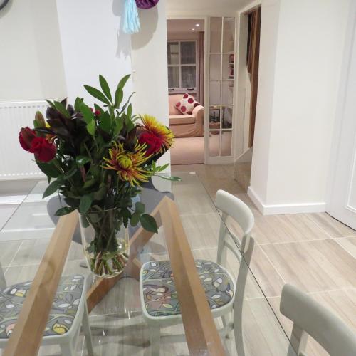 a glass table with a vase of flowers on it at Frog Palace - Secure Parking-Outside Area-Topsham-Exeter-Beach-Chiefs-WiFi in Topsham
