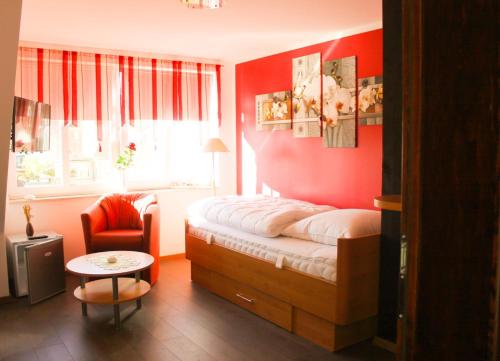 ノイシュタット・グレヴェにあるGästehaus Burgblickの赤い壁のベッドルーム1室、ベッド1台、椅子1脚が備わります。