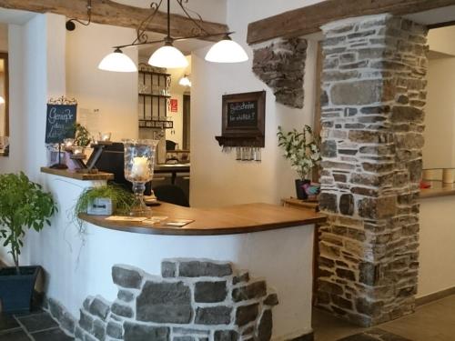 a bar in a restaurant with a stone wall at Das Gästehaus in Valwig in Valwig