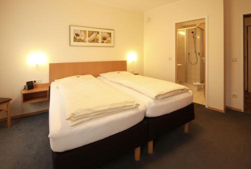 a hotel room with two beds and a bathroom at Hotel Geschermann in Sendenhorst