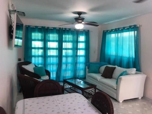 a living room with blue curtains and a couch at La Gaviota B3 in Juan Dolio