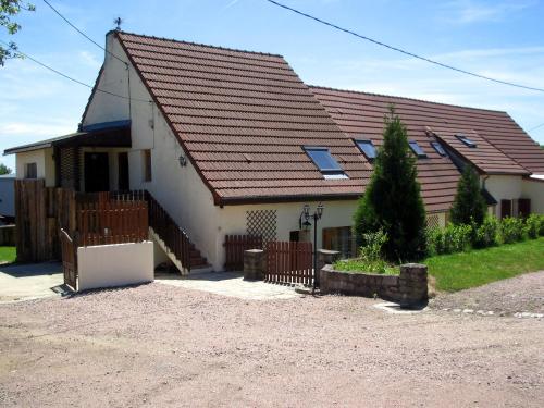 une maison avec un toit marron et une clôture dans l'établissement Gites de Montvaltin, à Le Breuil