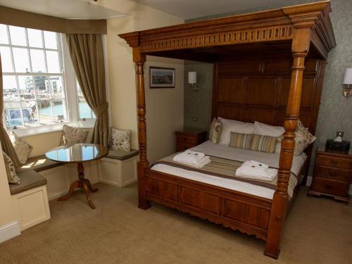1 dormitorio con cama de madera con dosel y mesa en The George, en West Bay