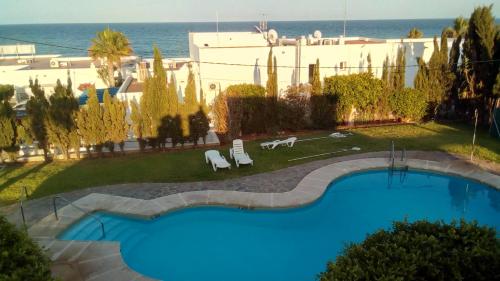 Hotel Mojácar Playa في موجاكار: إطلالة علوية على مسبح وكراسي وعلى المحيط