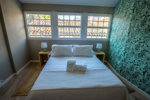 a bedroom with a large bed with two windows at Secret Garden Suites in Bragança in Bragança