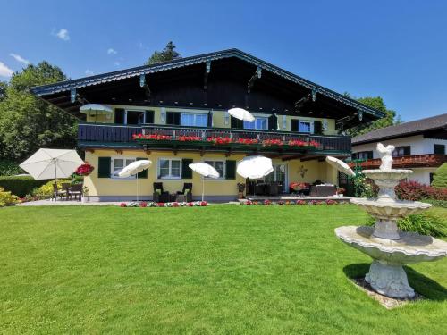a large building with a fountain in the yard at Ferienwohnungen Thalmeier in Sankt Gilgen