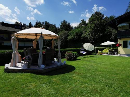 a gazebo with chairs and an umbrella in a yard at Ferienwohnungen Thalmeier in Sankt Gilgen