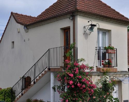 a white house with flowers on the balcony at Gite Ty-Coz in Charly-sur-Marne