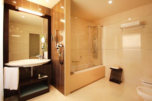 a bathroom with a shower, sink, and toilet at BessaHotel Boavista in Porto
