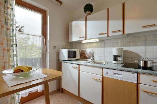 kuchnia z białymi szafkami i miską owoców na ladzie w obiekcie Haus Landmann w mieście Ellmau