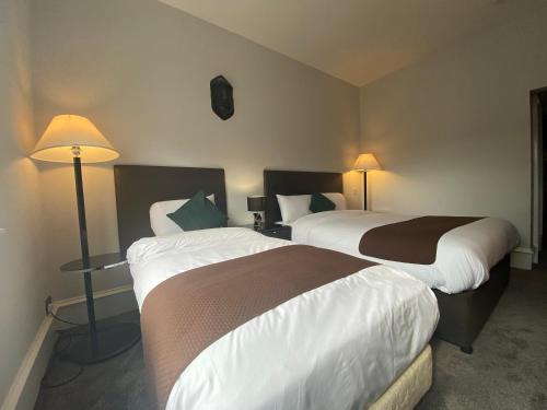 two beds in a hotel room with two lamps at No6 West Coates in Edinburgh
