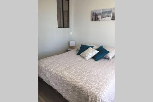 une chambre avec un lit avec des oreillers bleus dessus dans l'établissement L'esplanade, à Saint-Jean-de-Monts