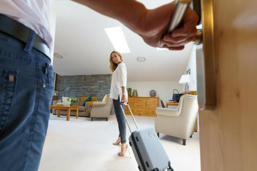 a woman standing in a living room with a suitcase at Landhotel Gockelwirt in Eisenberg