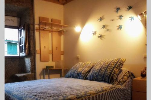 Un dormitorio con una cama con pájaros en la pared. en Casa da Mininha, en Ponte da Barca