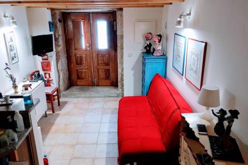 a red couch in a living room with a door at Casa da Mininha in Ponte da Barca