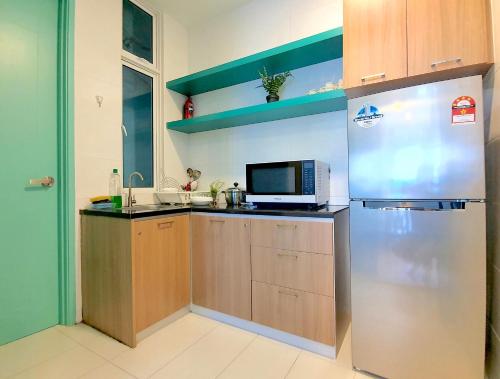 a kitchen with a refrigerator and a microwave at The Wave Suites Melaka in Melaka