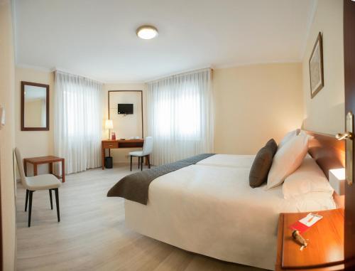 Habitación de hotel con cama grande y escritorio. en Hotel San Lorenzo en Santiago de Compostela