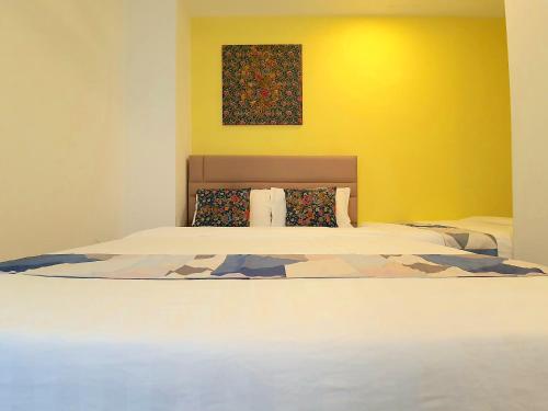 a bedroom with a large bed with a yellow wall at The Wave Suites Melaka in Melaka