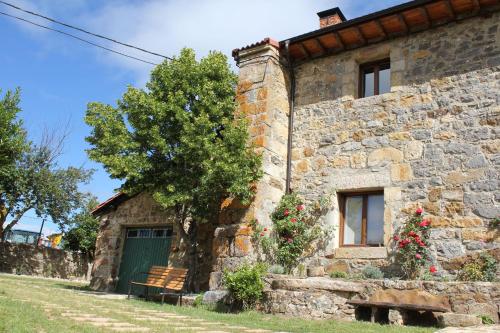 una vieja casa de piedra con una puerta verde y un árbol en La Casa del Diezmo de la Montaña Palentina, en Redondo