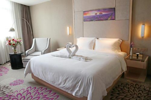 a hotel room with two swans towels on a bed at Lavande Hotel Huizhou High-speed Railway South Station Wanlian Square in Huizhou