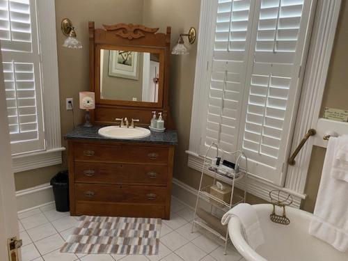 a bathroom with a sink and a mirror and a tub at Trowell Historic Inn in Jesup