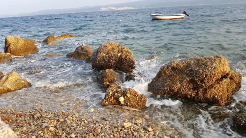 a boat in the water next to some rocks at Rumenović in Stanići