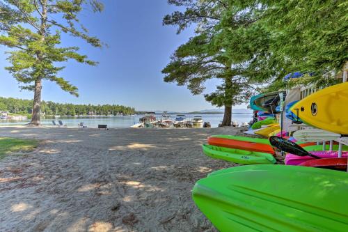 a row of kayaks lined up on a beach at Lake Getaway Walk Across Street to Private Beach! in Gilford