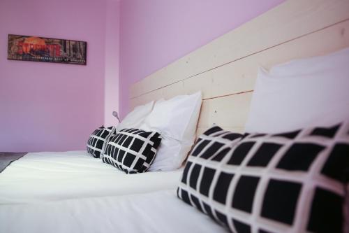 a bedroom with a white bed with black and white pillows at Hôtel La Couronne in Marmande