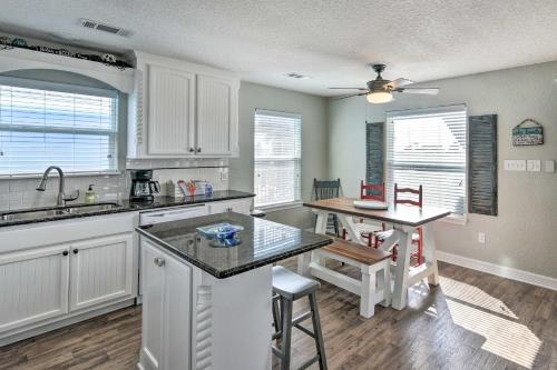 a kitchen with white cabinets and a table and a counter at 2 Blocks to Gulf Surfside Beach Family Home! in Surfside Beach