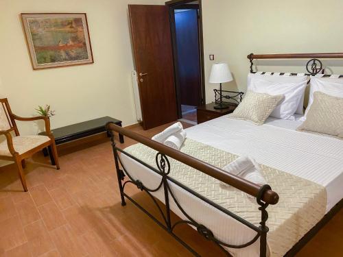 een slaapkamer met een bed en een stoel bij Seaside "Stone & Light Villa" close to Aegina City in Khlóï