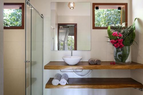 a bathroom with a sink and a shower with a mirror at Natura Spa Guest House in Arraial D'Ajuda in Arraial d'Ajuda