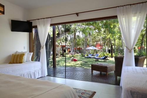 a bedroom with two beds and a sliding glass door at Natura Spa Guest House in Arraial D'Ajuda in Arraial d'Ajuda